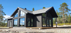 Moderna privātmāja ar lieliem logiem un dedzināta koka imitācijas ārējo fasādi