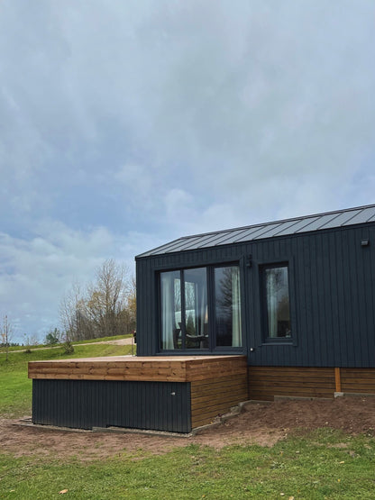 Moderna koka karkasa moduļu māja ar terasi un vitrīnas logiem, sānskats