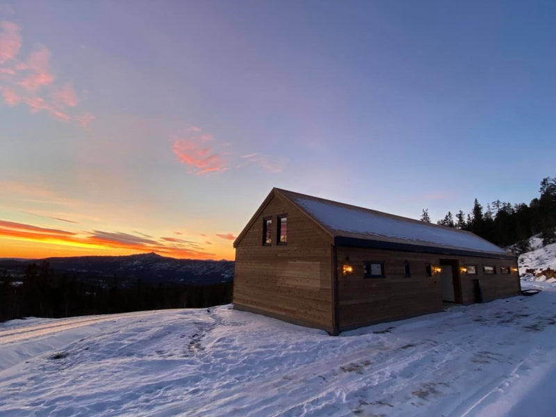 Moderna koka karkasa paneļu privātmāja Latvijā ar pagalma skatu uz saulrietu