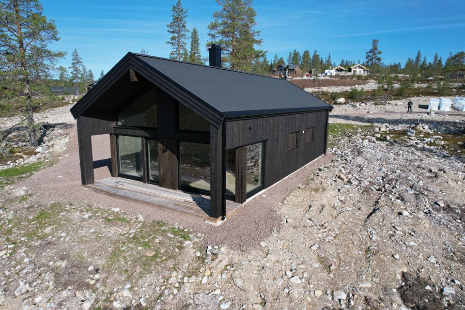 Skandināvu stila privātmāja ar dedzināta koka imitācijas fasādi, plašiem logiem un plašu apbūves laukum